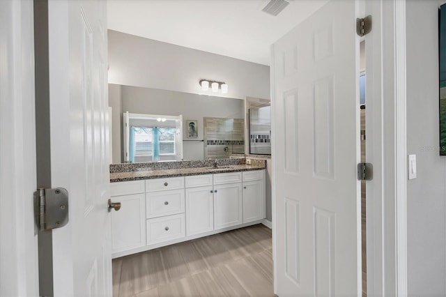 full bathroom with visible vents, vanity, and tiled shower