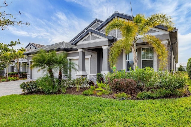 19807 Bridgetown Loop, Venice, FL 34293 - view of front of house featuring a garage, driveway, a front lawn, stone siding, and stucco siding