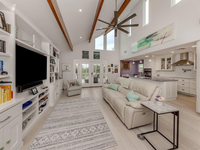 living room with a towering ceiling, french doors, beamed ceiling, light wood-type flooring, and ceiling fan