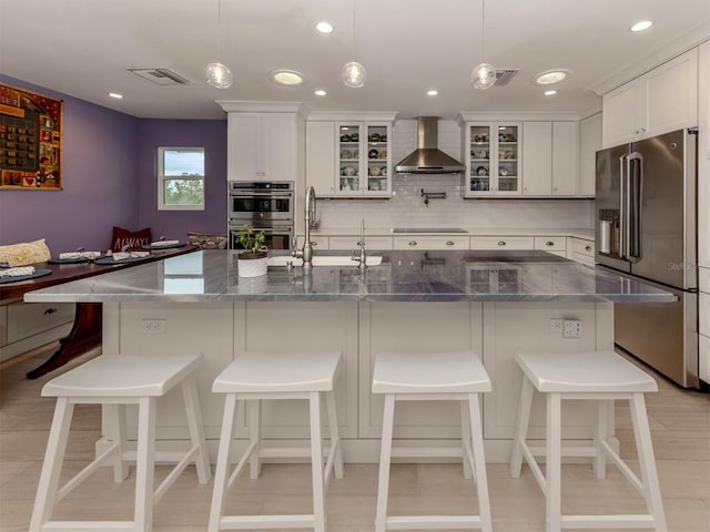 kitchen featuring stainless steel appliances, white cabinetry, a large island, and wall chimney range hood