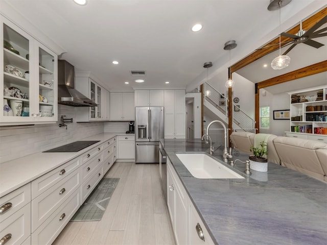 kitchen with black electric stovetop, high end refrigerator, wall chimney range hood, pendant lighting, and sink