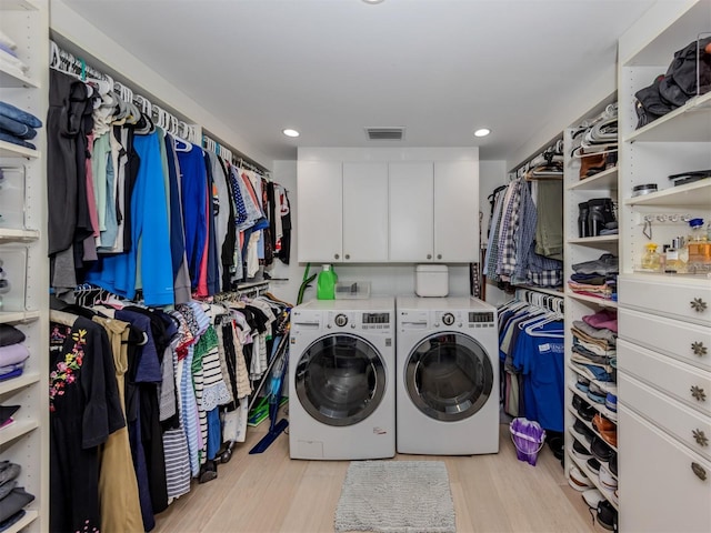 washroom featuring cabinets, independent washer and dryer, and light hardwood / wood-style flooring