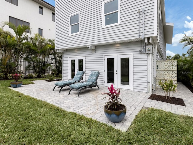 rear view of property with a lawn, french doors, and a patio area