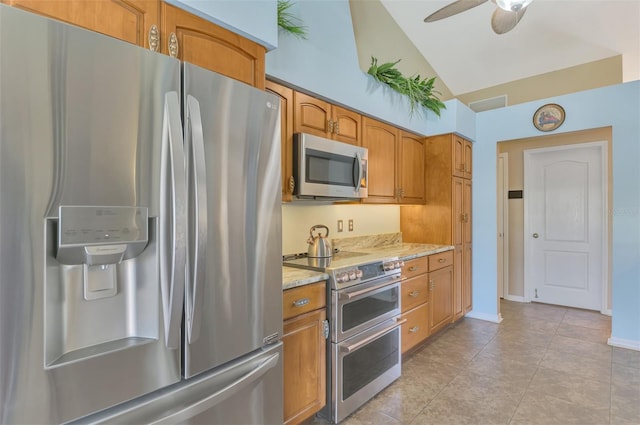 kitchen featuring light tile patterned flooring, lofted ceiling, light stone counters, ceiling fan, and stainless steel appliances