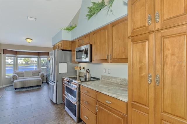 kitchen featuring appliances with stainless steel finishes, light stone countertops, and light tile patterned floors