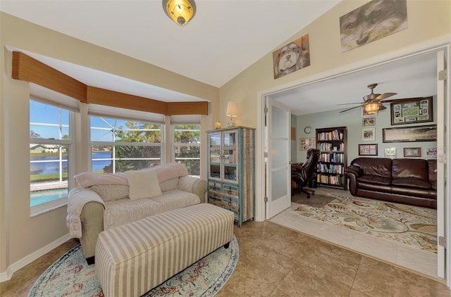 tiled living room with a water view, lofted ceiling, and ceiling fan