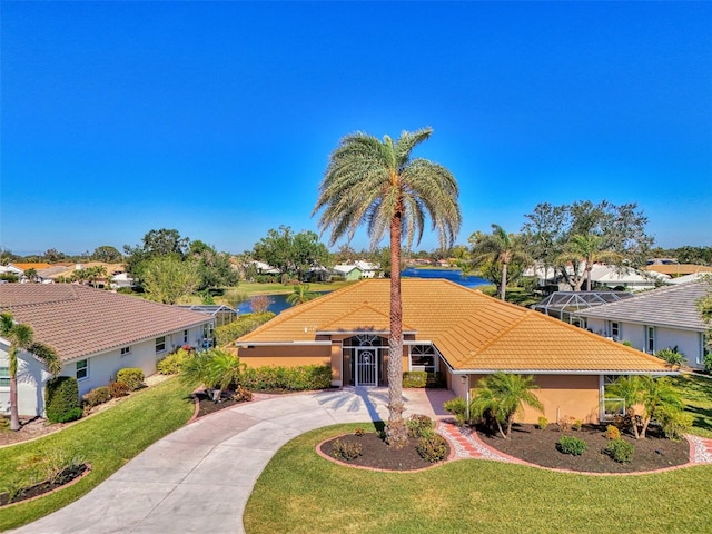 view of front of house with stucco siding, curved driveway, a tile roof, and a front lawn