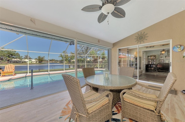 sunroom featuring a ceiling fan, a water view, and a pool