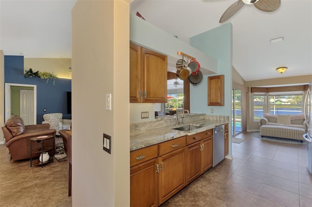 kitchen featuring ceiling fan, light stone counters, a sink, dishwasher, and lofted ceiling
