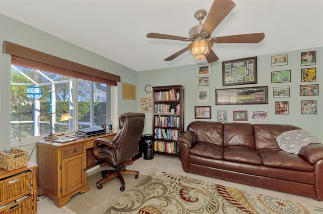 office space with a ceiling fan and light carpet