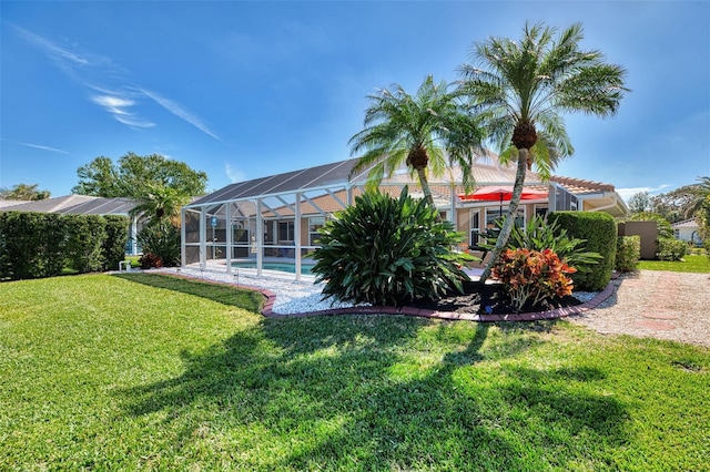 rear view of property with a lawn, an outdoor pool, and glass enclosure