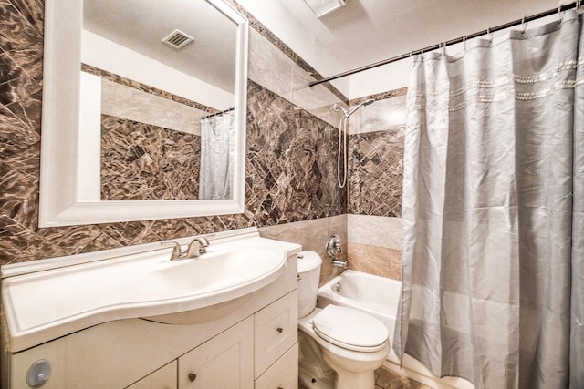 full bathroom with tile walls, toilet, vanity, and shower / bathtub combination with curtain