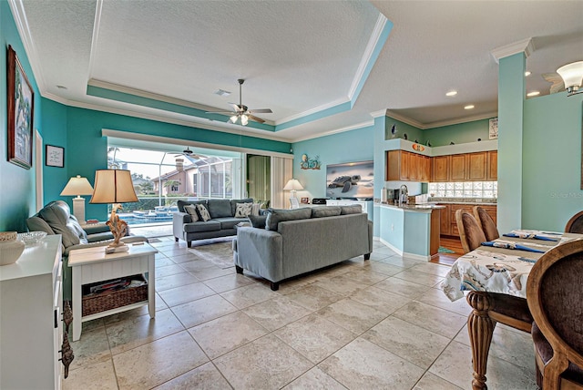 living room with ceiling fan, crown molding, a raised ceiling, and a textured ceiling