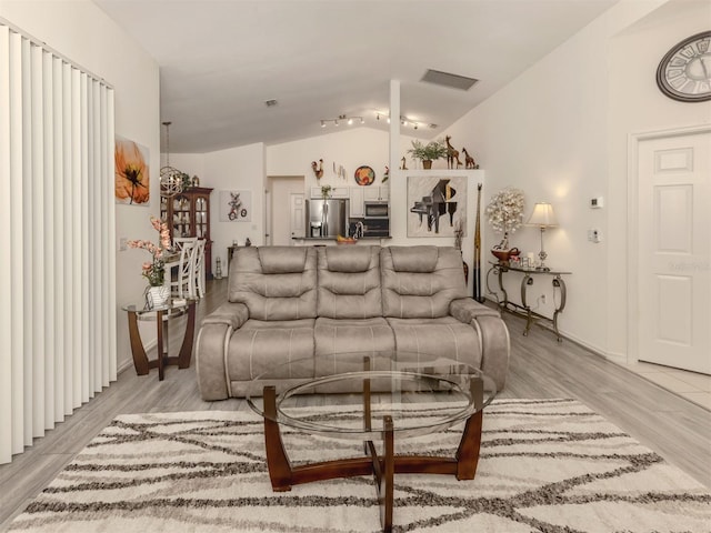 living room featuring light wood-type flooring and vaulted ceiling