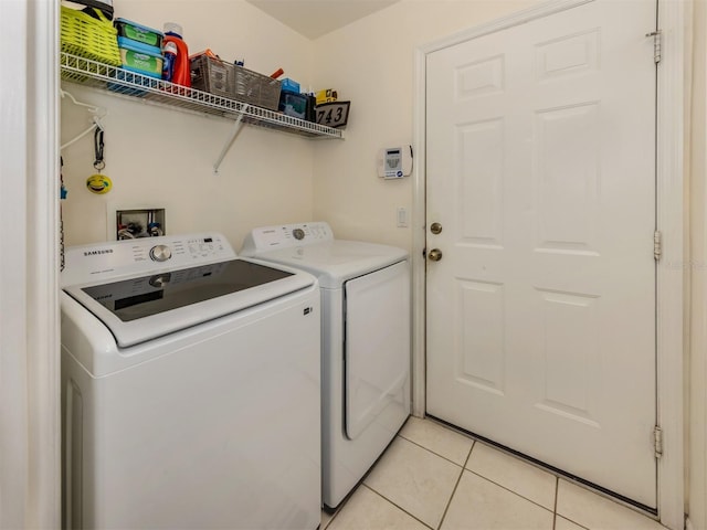 clothes washing area featuring washer and clothes dryer and light tile patterned floors