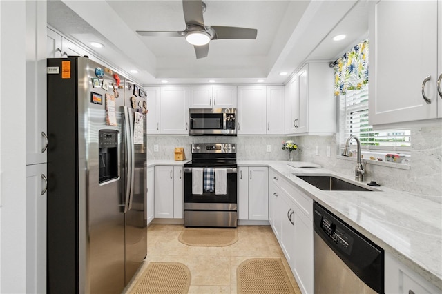 kitchen featuring a raised ceiling, tasteful backsplash, sink, white cabinets, and stainless steel appliances