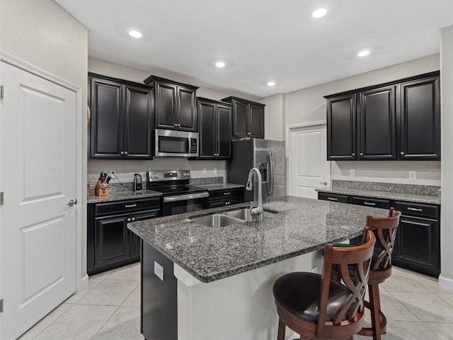 kitchen with a kitchen bar, sink, light tile patterned flooring, an island with sink, and stainless steel appliances