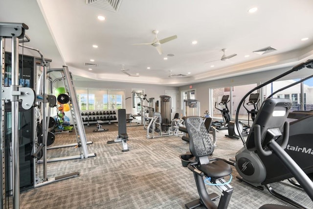 exercise room with ceiling fan and a tray ceiling