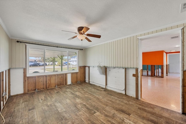 empty room with ceiling fan, hardwood / wood-style flooring, ornamental molding, and a textured ceiling