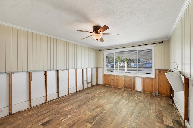 empty room featuring ceiling fan, ornamental molding, hardwood / wood-style floors, and a textured ceiling