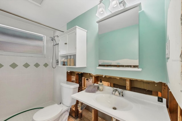 bathroom featuring tiled shower, toilet, and sink