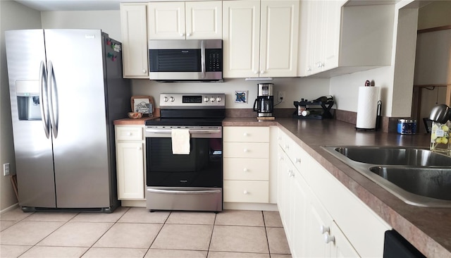 kitchen featuring sink, stainless steel appliances, white cabinetry, and light tile patterned floors