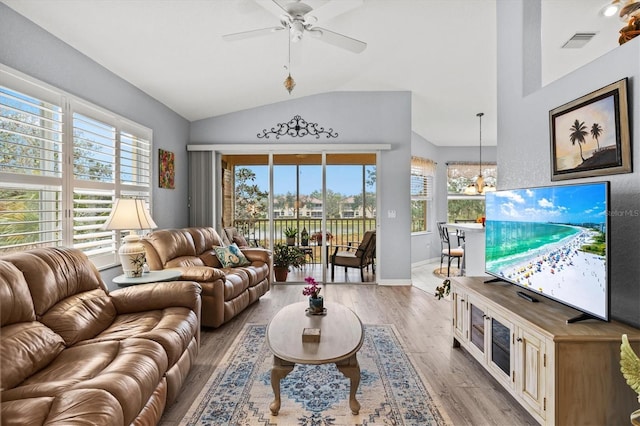 living room with vaulted ceiling, ceiling fan with notable chandelier, and light hardwood / wood-style flooring