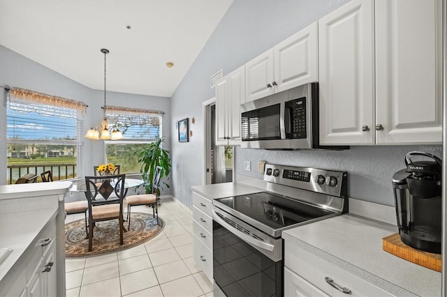 kitchen with stainless steel appliances, vaulted ceiling, light tile patterned floors, and white cabinets