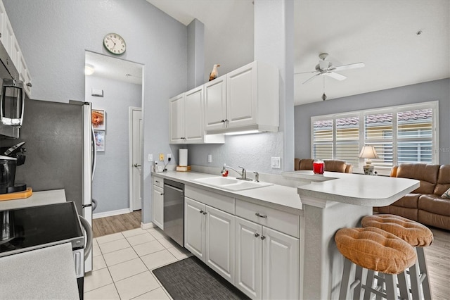 kitchen featuring sink, white cabinetry, appliances with stainless steel finishes, a kitchen breakfast bar, and kitchen peninsula