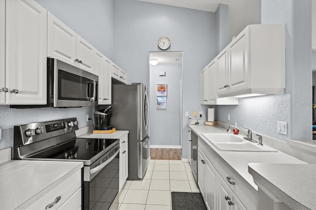 kitchen with white cabinetry, appliances with stainless steel finishes, sink, and light tile patterned floors