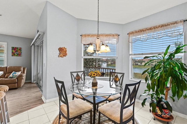 dining space with a water view, light tile patterned floors, and a chandelier