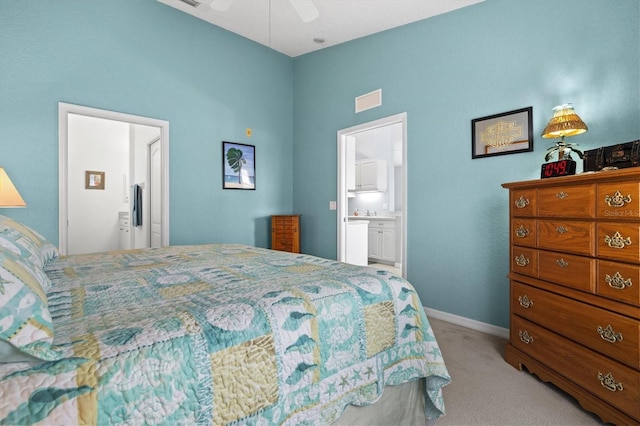 bedroom featuring light colored carpet, ceiling fan, and ensuite bathroom