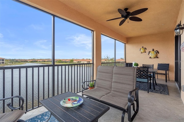 sunroom / solarium featuring a wealth of natural light, ceiling fan, and a water view