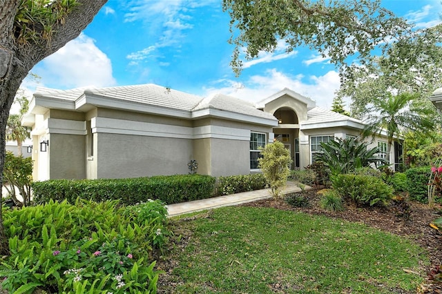 view of front of home with a front yard, a tile roof, and stucco siding