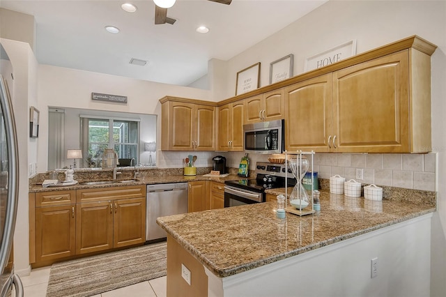 kitchen with sink, light stone counters, tasteful backsplash, appliances with stainless steel finishes, and kitchen peninsula