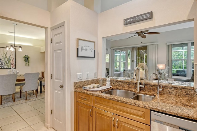 kitchen featuring sink, light tile patterned floors, dishwasher, hanging light fixtures, and light stone counters