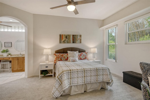 bedroom featuring ceiling fan, ensuite bath, sink, and light carpet