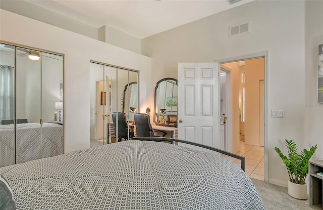 tiled bedroom featuring lofted ceiling and two closets