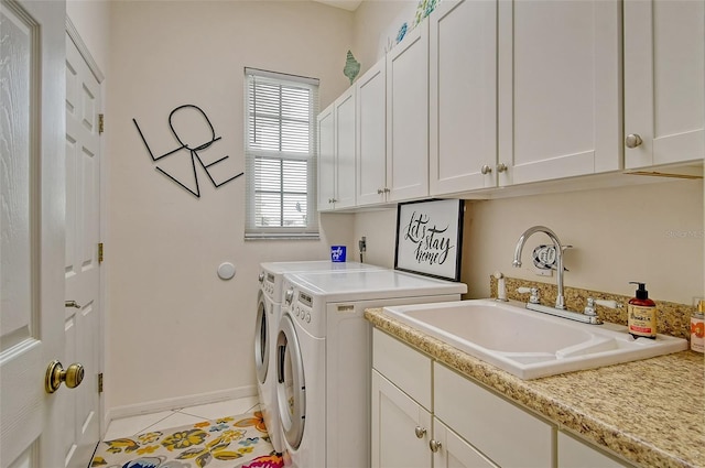 clothes washing area featuring cabinets, sink, light tile patterned floors, and washer and clothes dryer