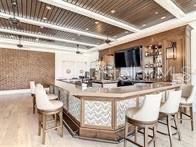 bar with a community bar, beamed ceiling, and wood finished floors