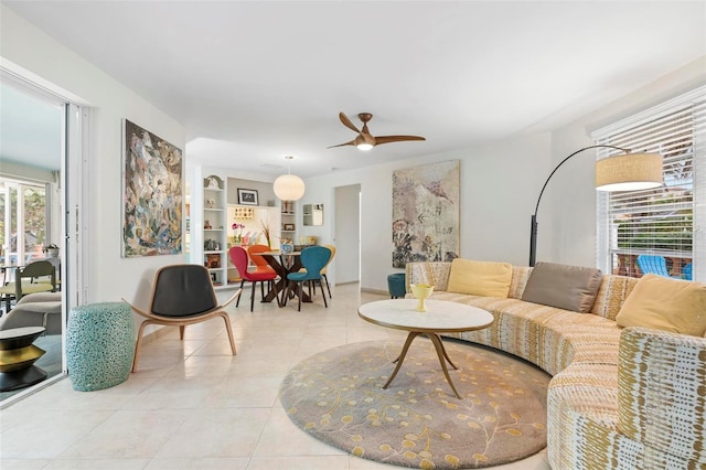 tiled living room with ceiling fan and built in shelves