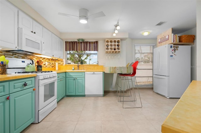 kitchen with light tile patterned floors, ceiling fan, backsplash, white appliances, and white cabinets