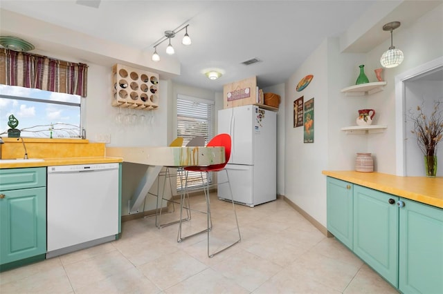 kitchen featuring light tile patterned floors, white appliances, green cabinetry, and pendant lighting