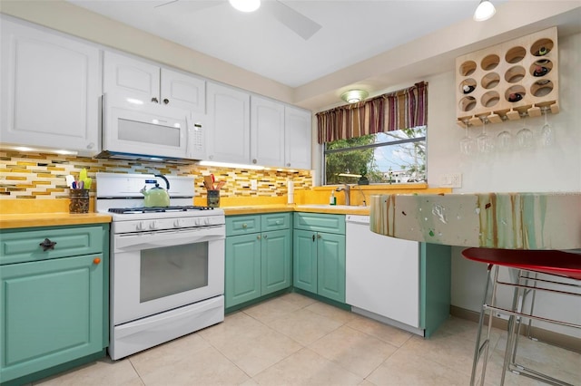 kitchen featuring white cabinetry, backsplash, white appliances, light tile patterned flooring, and sink