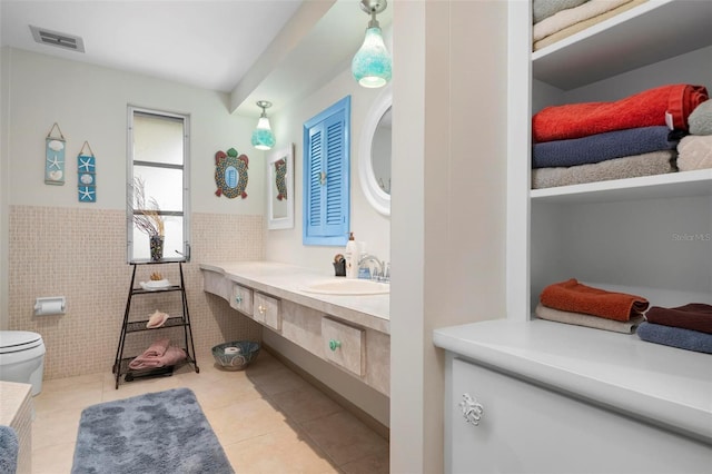 bathroom with tile patterned flooring, tile walls, sink, and toilet