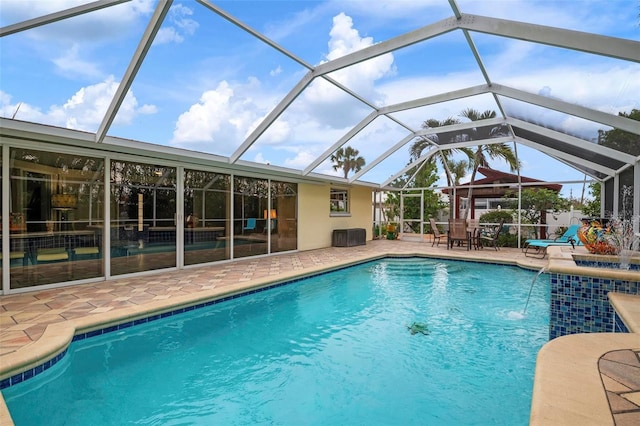 view of pool with a lanai, pool water feature, and a patio area