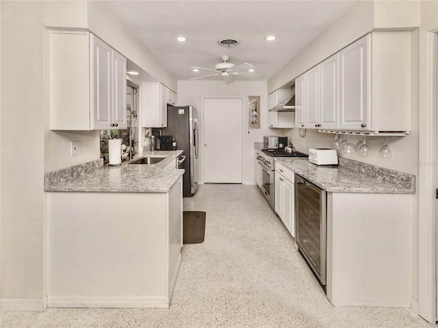 kitchen featuring stainless steel appliances, wall chimney exhaust hood, beverage cooler, and white cabinets