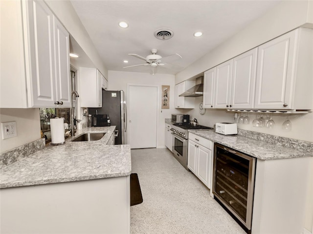 kitchen with wine cooler, sink, white cabinetry, stainless steel appliances, and wall chimney exhaust hood