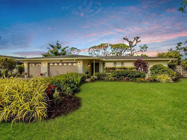 ranch-style home with a garage and a lawn