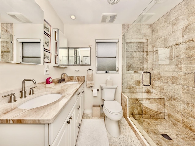 bathroom featuring toilet, a shower with shower door, and vanity